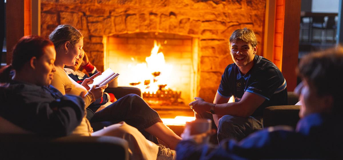 Image of friends chatting and reading by a warm fire